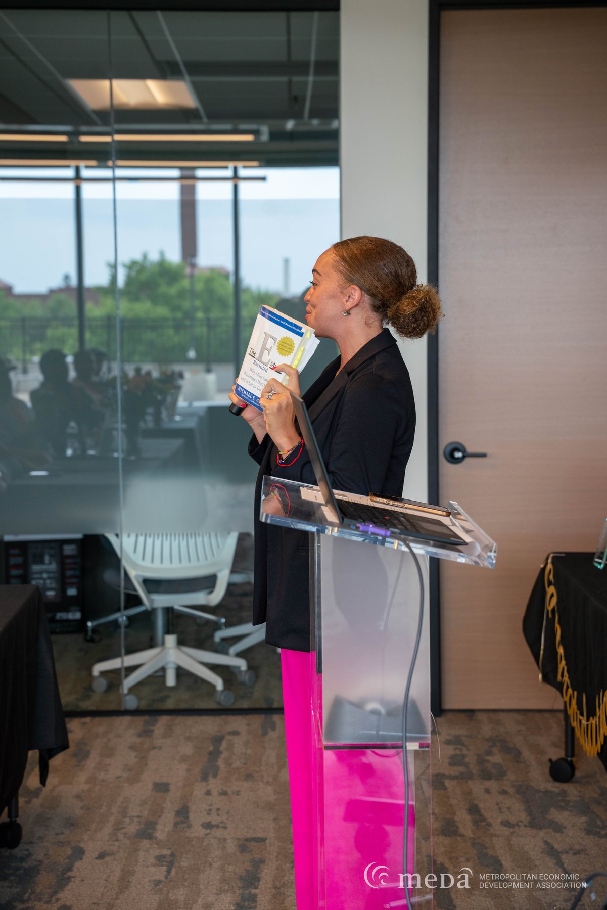 Alivia Boddie reading from her notes at a clear podium during a MEDA program session