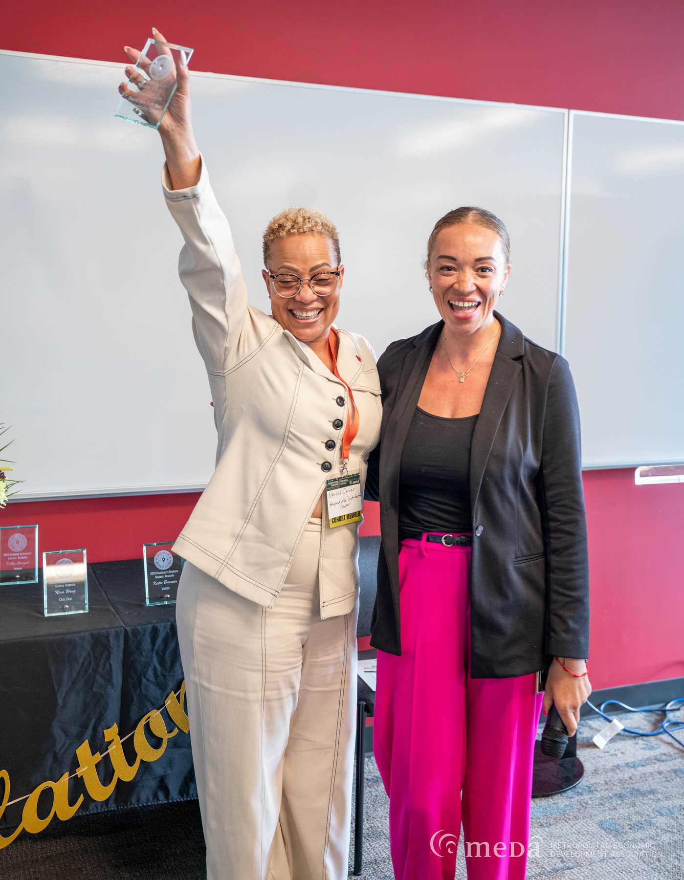 Alivia Boddie celebrating with a Roadmap to Business Success graduate who holds up an award