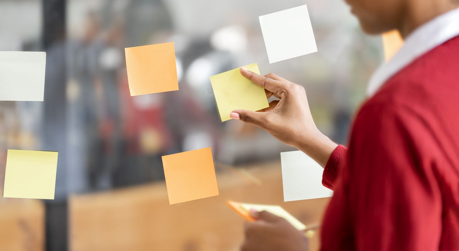 A person placing sticky notes on a glass wall during a planning session